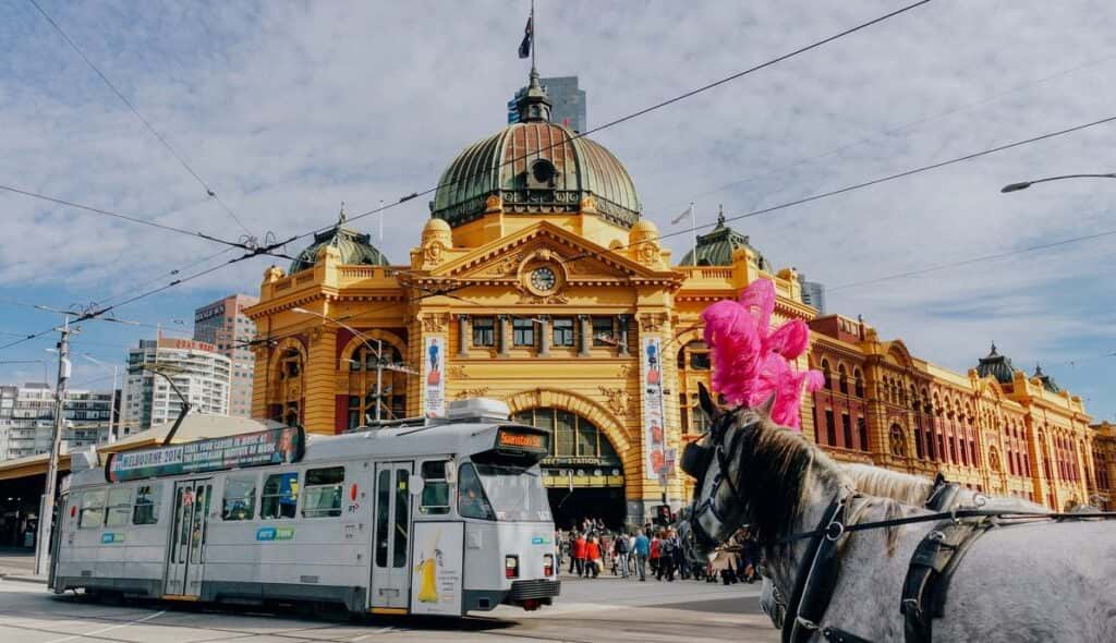 Solo trip, colourful view of Finders Station in the background, with a tram and horse carriage in front