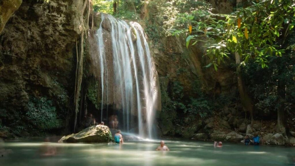 People swimming at a waterfall in Erawan National Park in Thailand